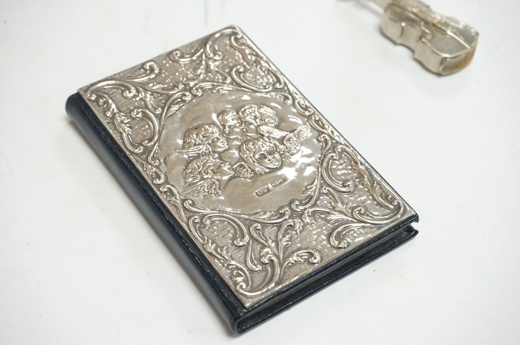A George V silver mounted glass whisky noggin, by Levi & Salaman, Birmingham, 1911, 10.2cm, together with a modern repousse silver mounted address book, by Keyford Frames Ltd, London, 1989 and a plated novelty violin ves